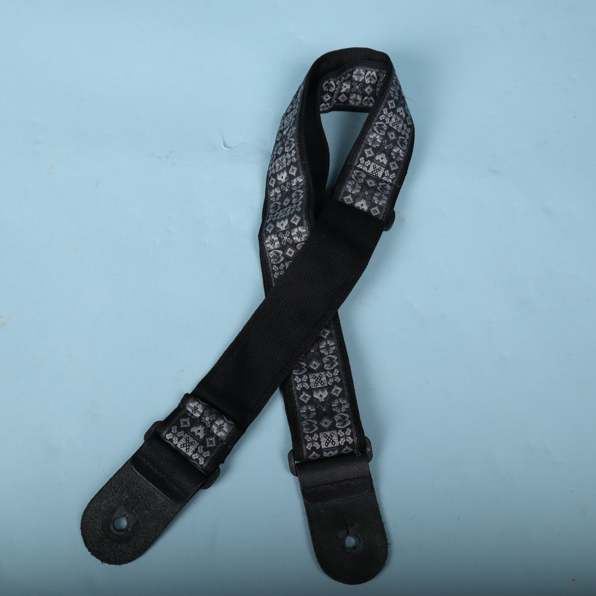 Full reverse view of the guitar strap showing black backing and leather ends.