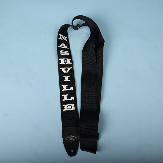 Full view of the black LM Products Nashville guitar strap on a light blue background