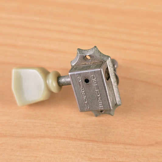 Close-up angled view of the stamped Gibson Deluxe tuner housing.