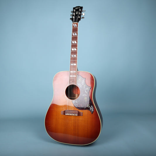 Full front view of the Gibson Hummingbird dreadnought acoustic guitar on a light blue background.