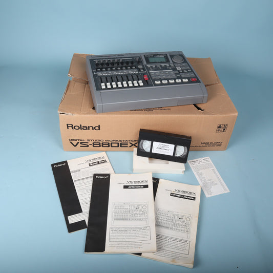 Angled view of Roland VS-880EX workstation resting on its original cardboard packaging alongside manuals.