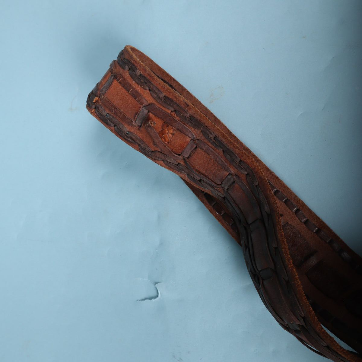 Detail of folded leather strap end showing hand-laced trim