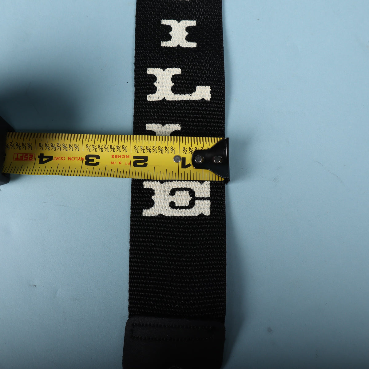 Close-up measurement across the black webbing strap confirming the 2-inch width