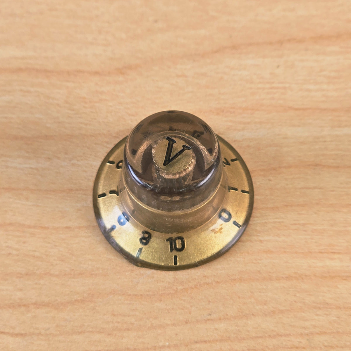 Front-facing top view of gold and transparent control knob with V marker