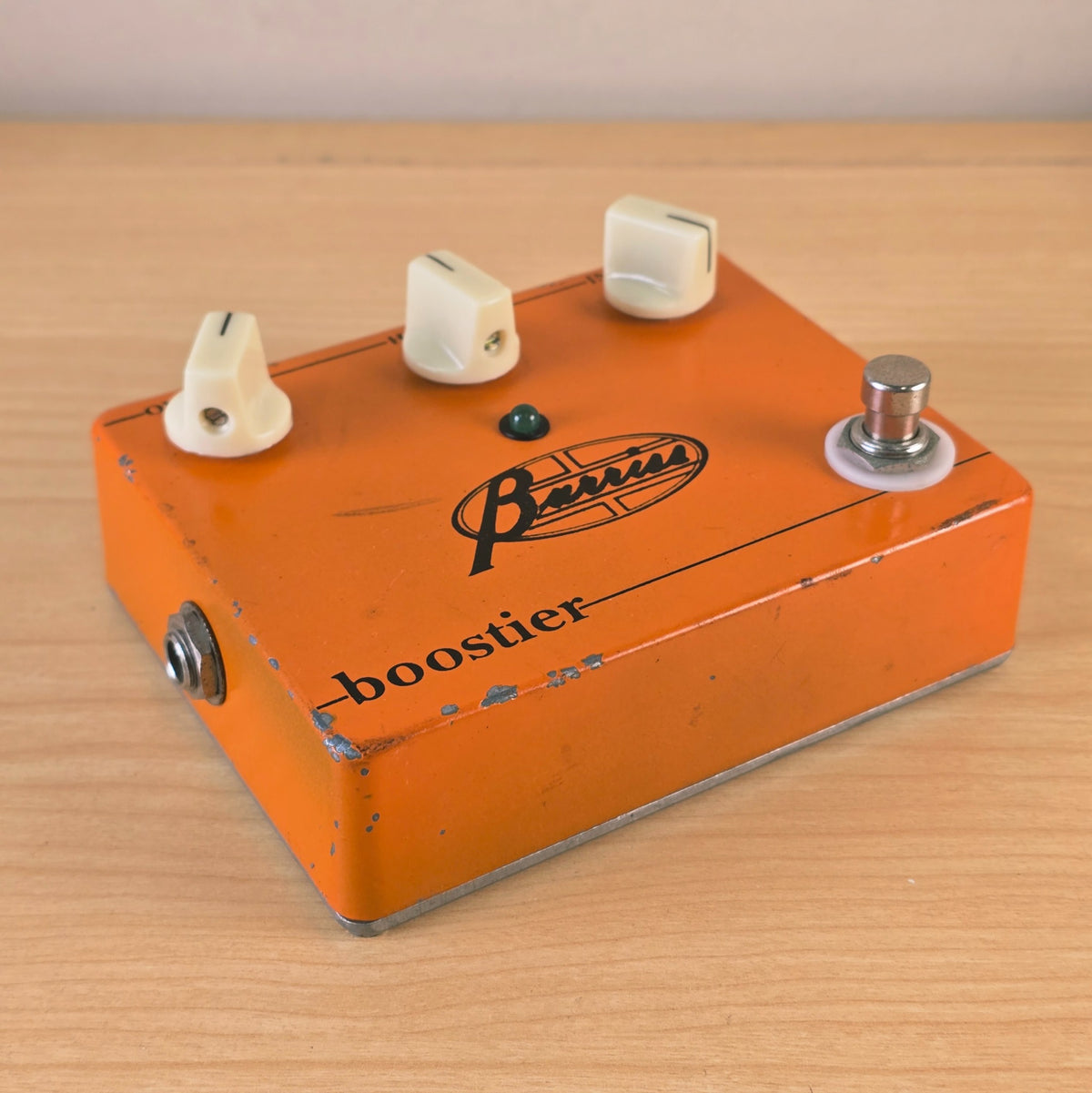 Low angle view of the Barriss Boostier pedal showing the front edge wear and footswitch.