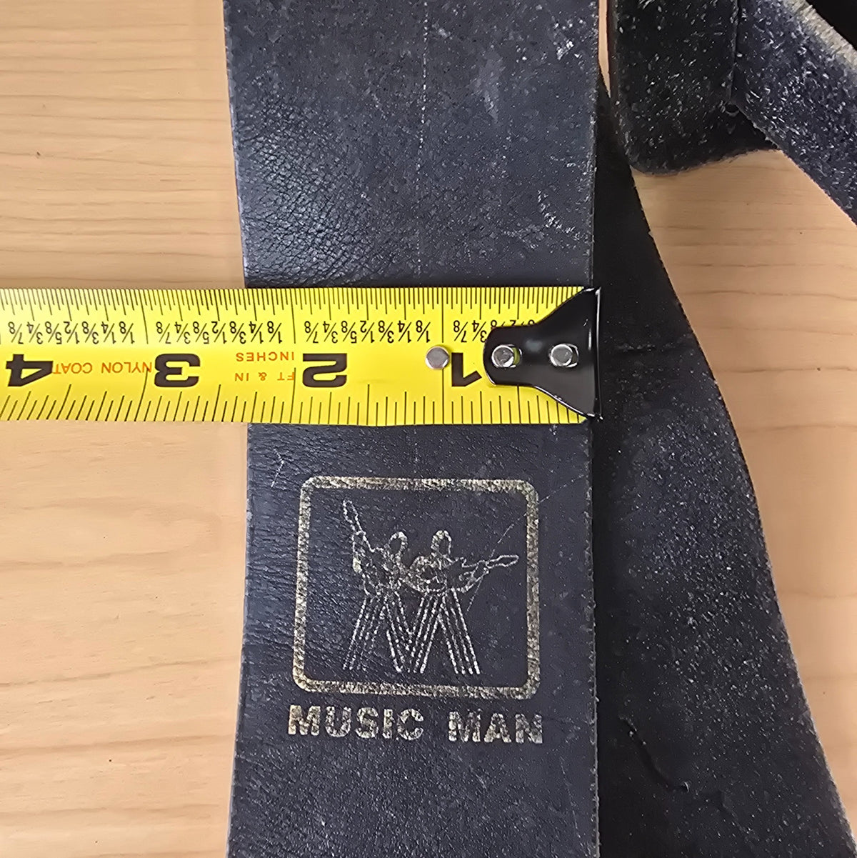 Width measurement of vintage Music Man black leather strap with tape measure showing 2.5 inches