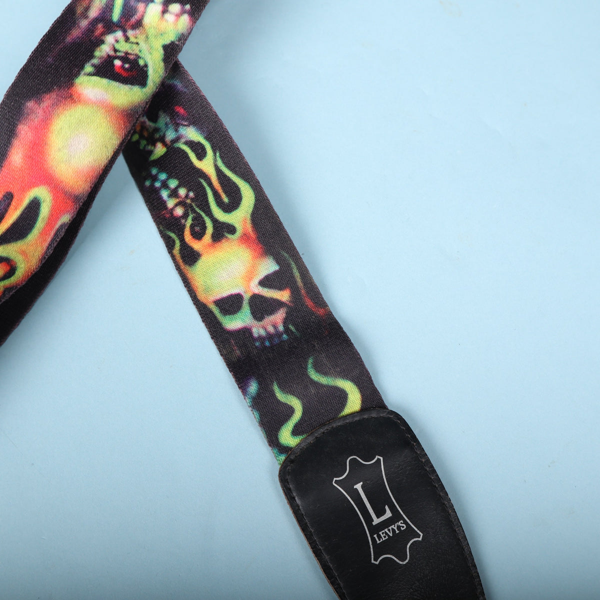 Angled view of the flaming skull webbing leading down to the leather end tab.