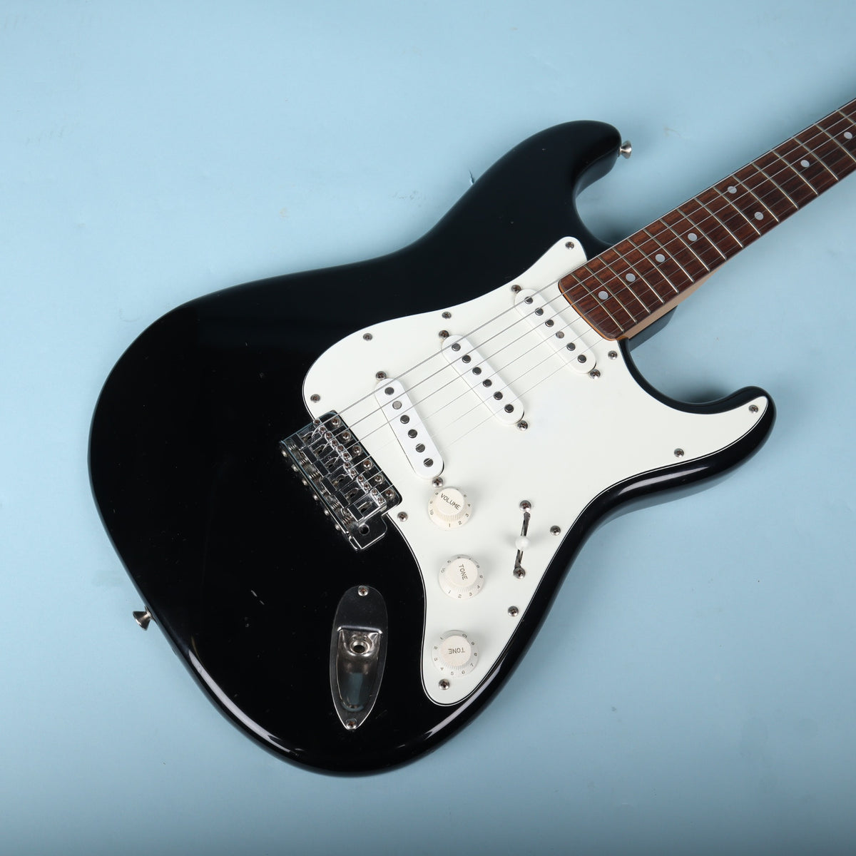 Angled front view of black guitar body showing pickguard, pickups, and chrome hardware. Published image details body contours