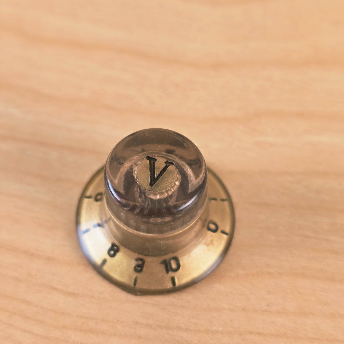 Angled top view of gold and transparent top hat knob with V marker