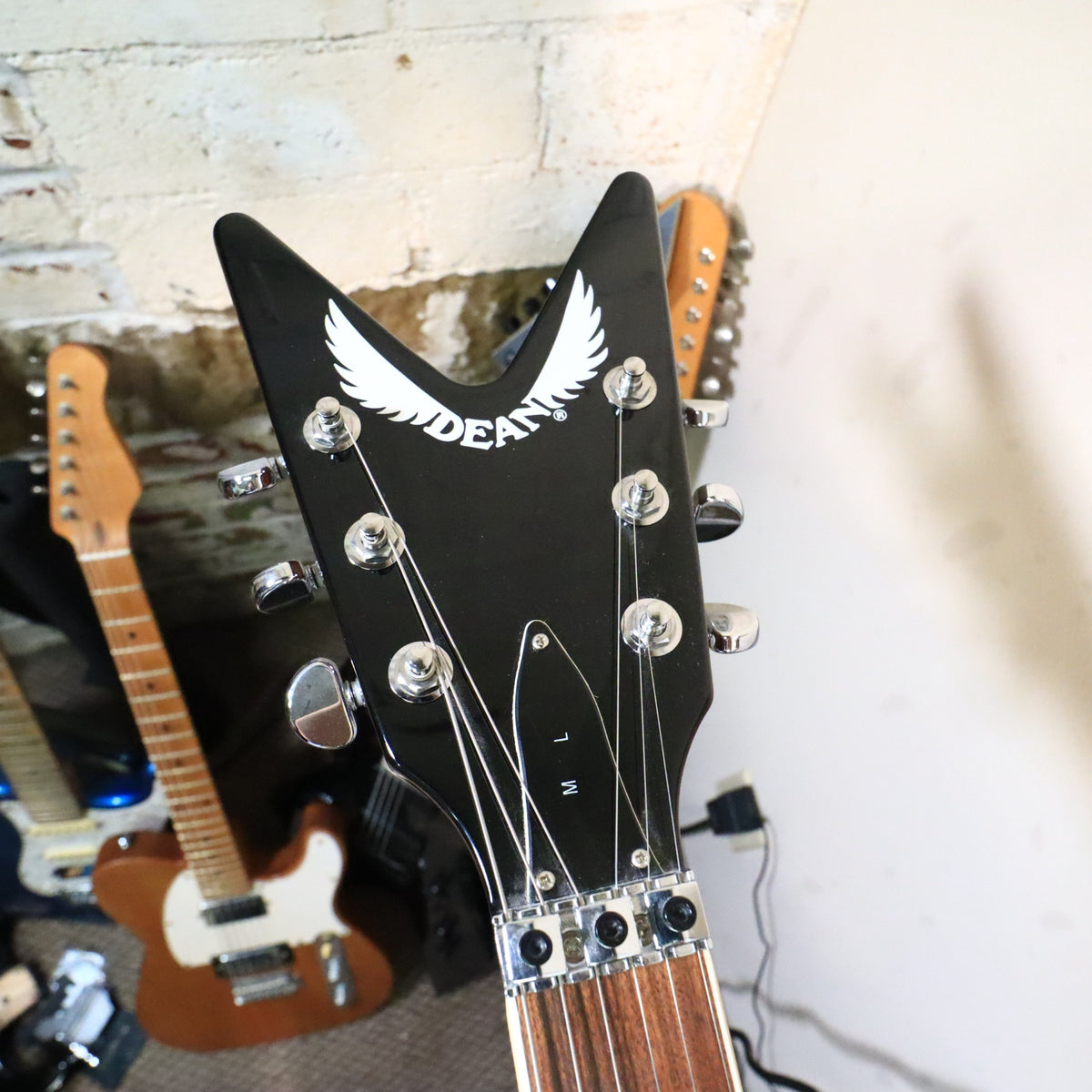 Headstock face of Dean ML guitar on workbench with locking nut and string retainer bar