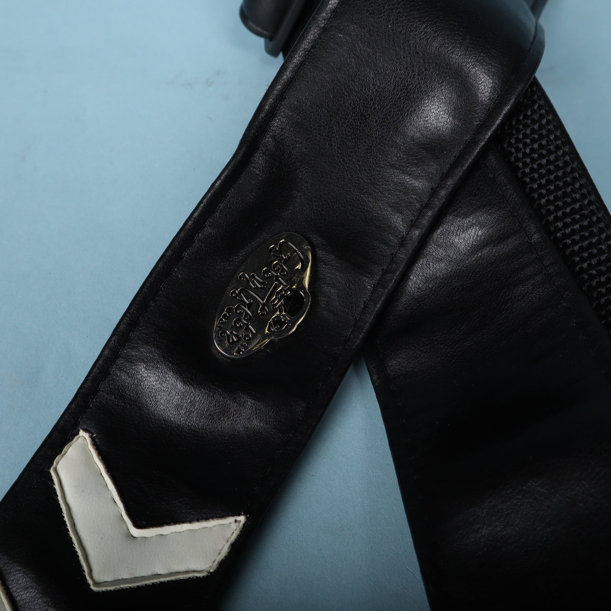 Close-up of the metal Get'm Get'm badge and top white chevron on the black strap face