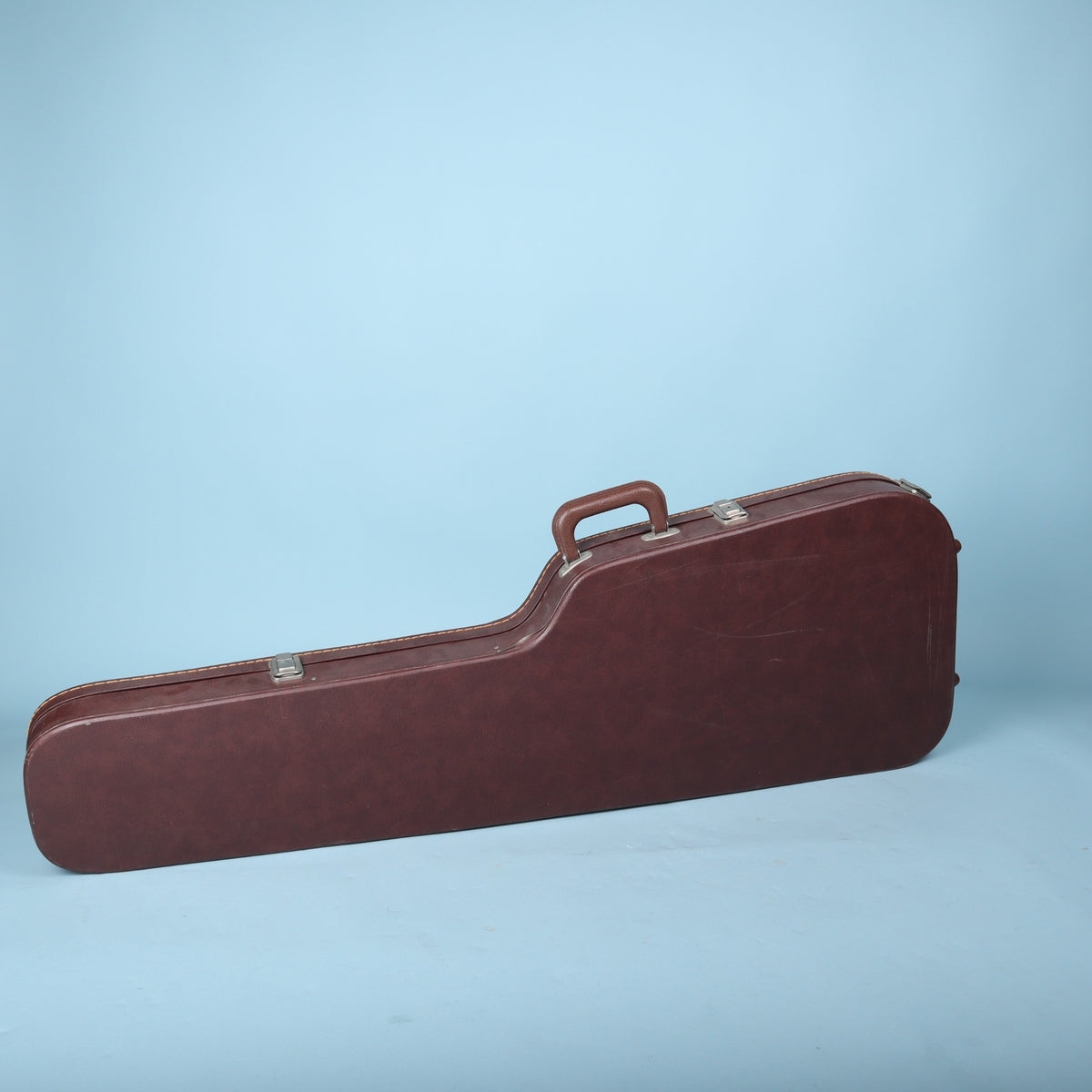 Back exterior view of the brown hardshell Ibanez guitar case showing the handle and latches.