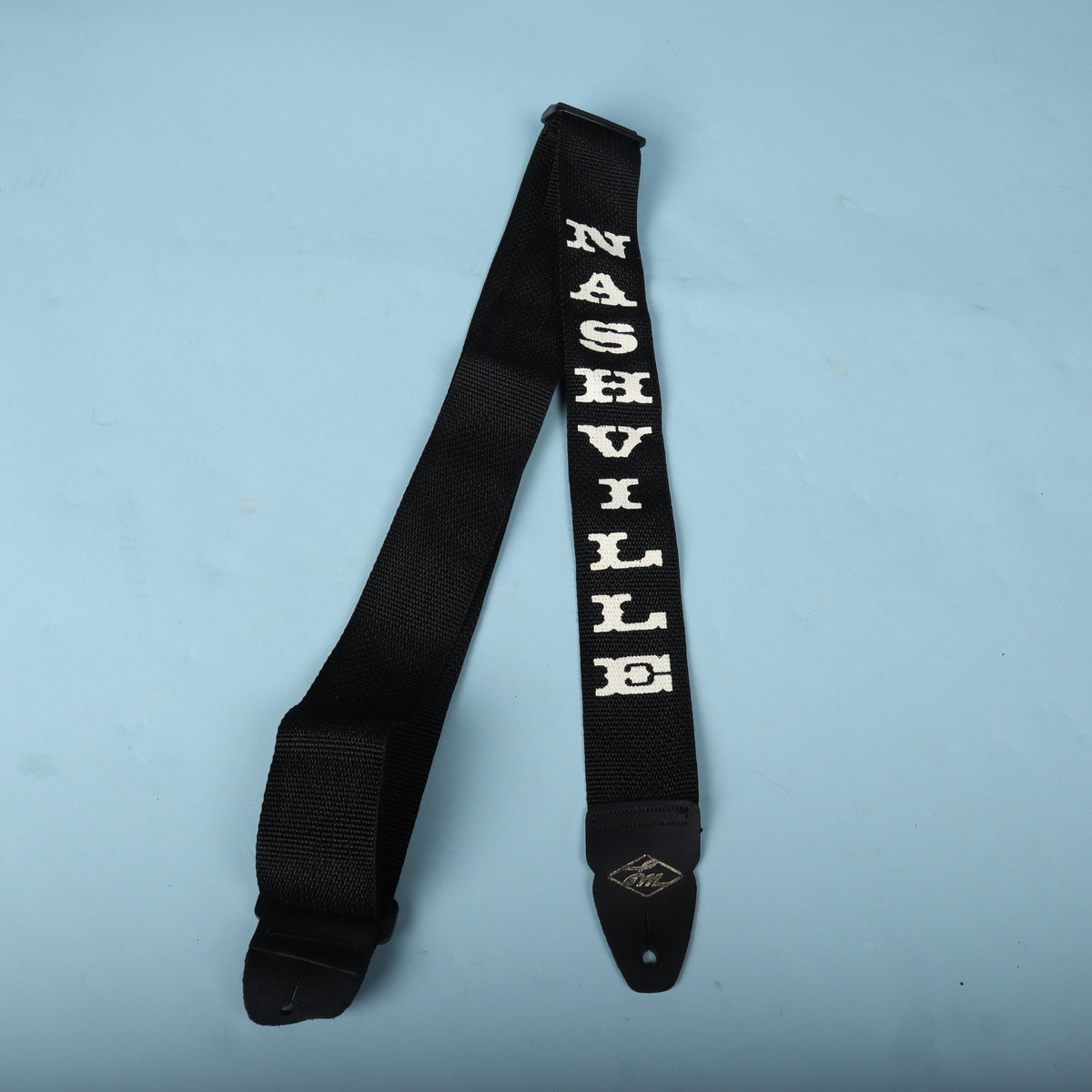 Overhead shot of the LM Products Nashville guitar strap laid out against a blue backdrop