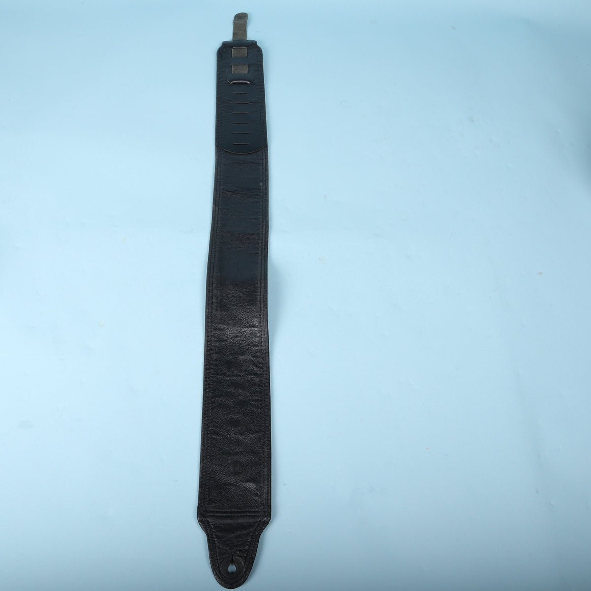 Full-length rear view of the black leather strap showing its padded lining and adjustable tail.