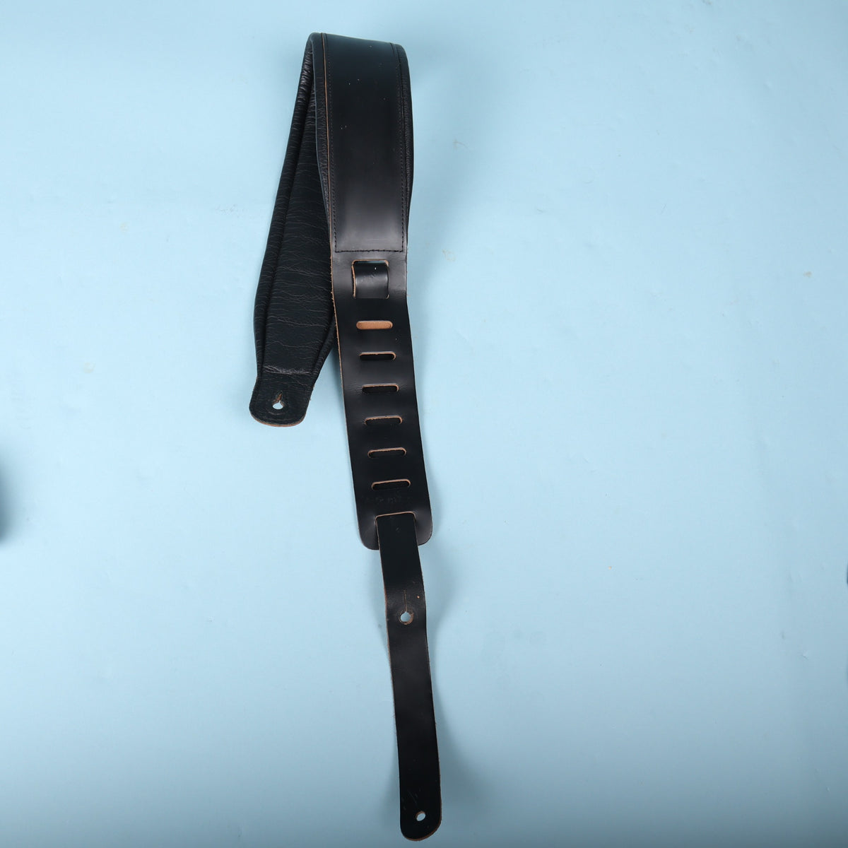 Levy's 3-inch padded leather bass strap folded with adjustment tail extended against a light blue background.