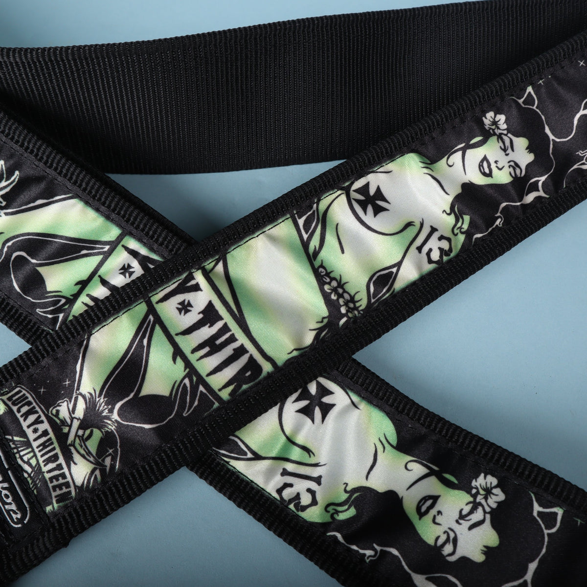 Close-up of the green and black zombie pinup graphic on the Dunlop Lucky 13 Dead Island strap.