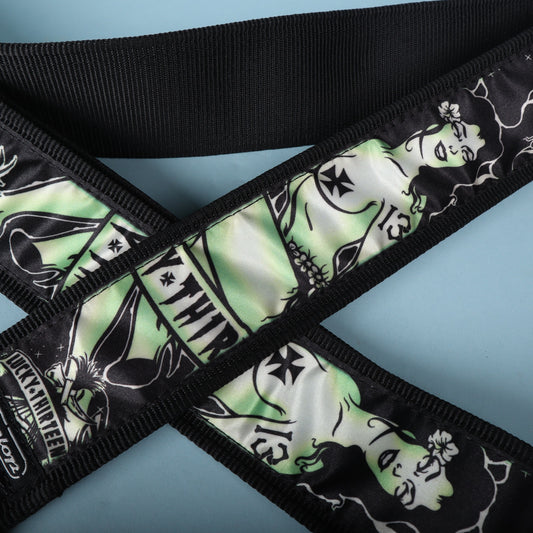 Close-up of the green and black zombie pinup graphic on the Dunlop Lucky 13 Dead Island strap.