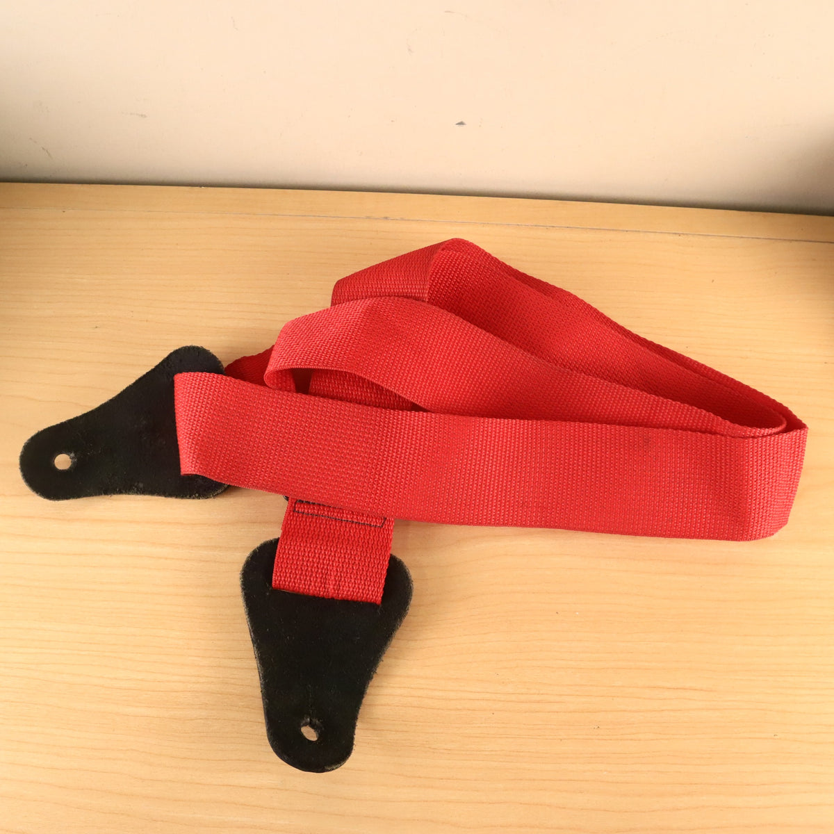 Back view of red GHS guitar strap showing underside of leather ends.