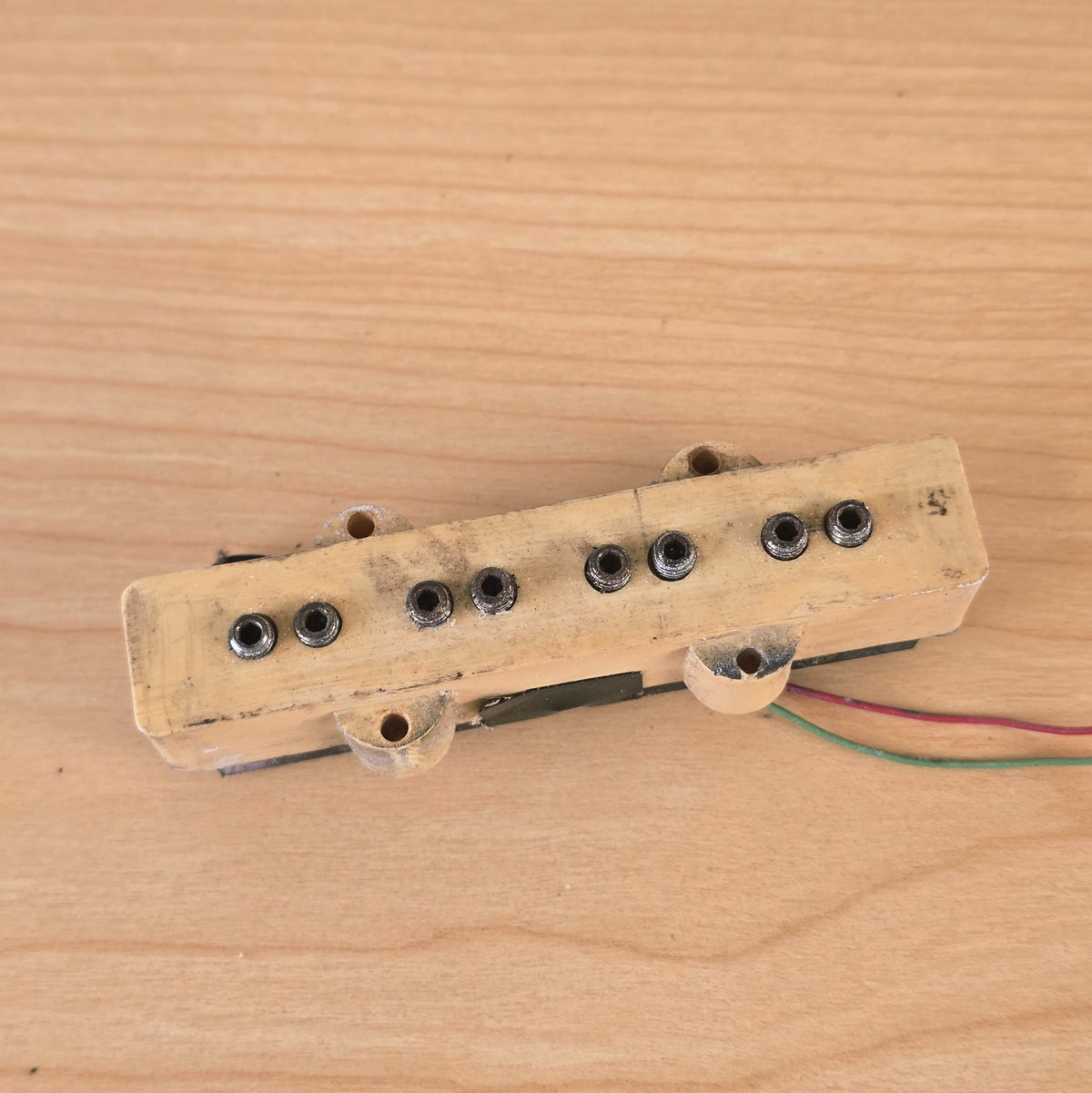 Close-up top view of cream bass pickup cover showing eight pole pieces.