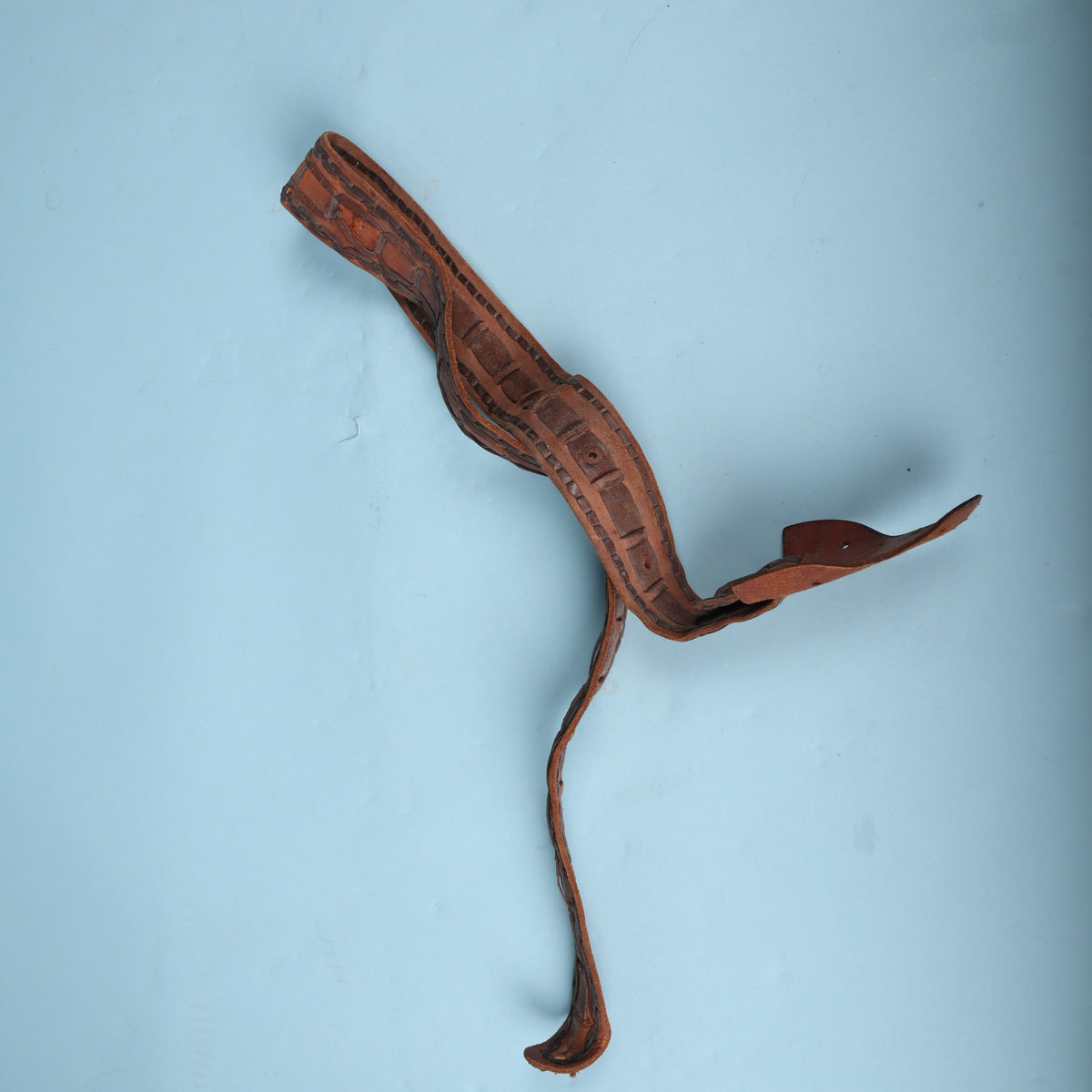 Vintage leather guitar strap loosely coiled on background