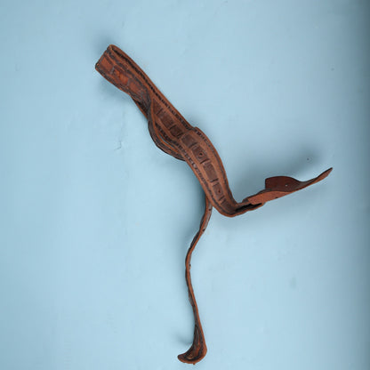 Vintage leather guitar strap loosely coiled on background