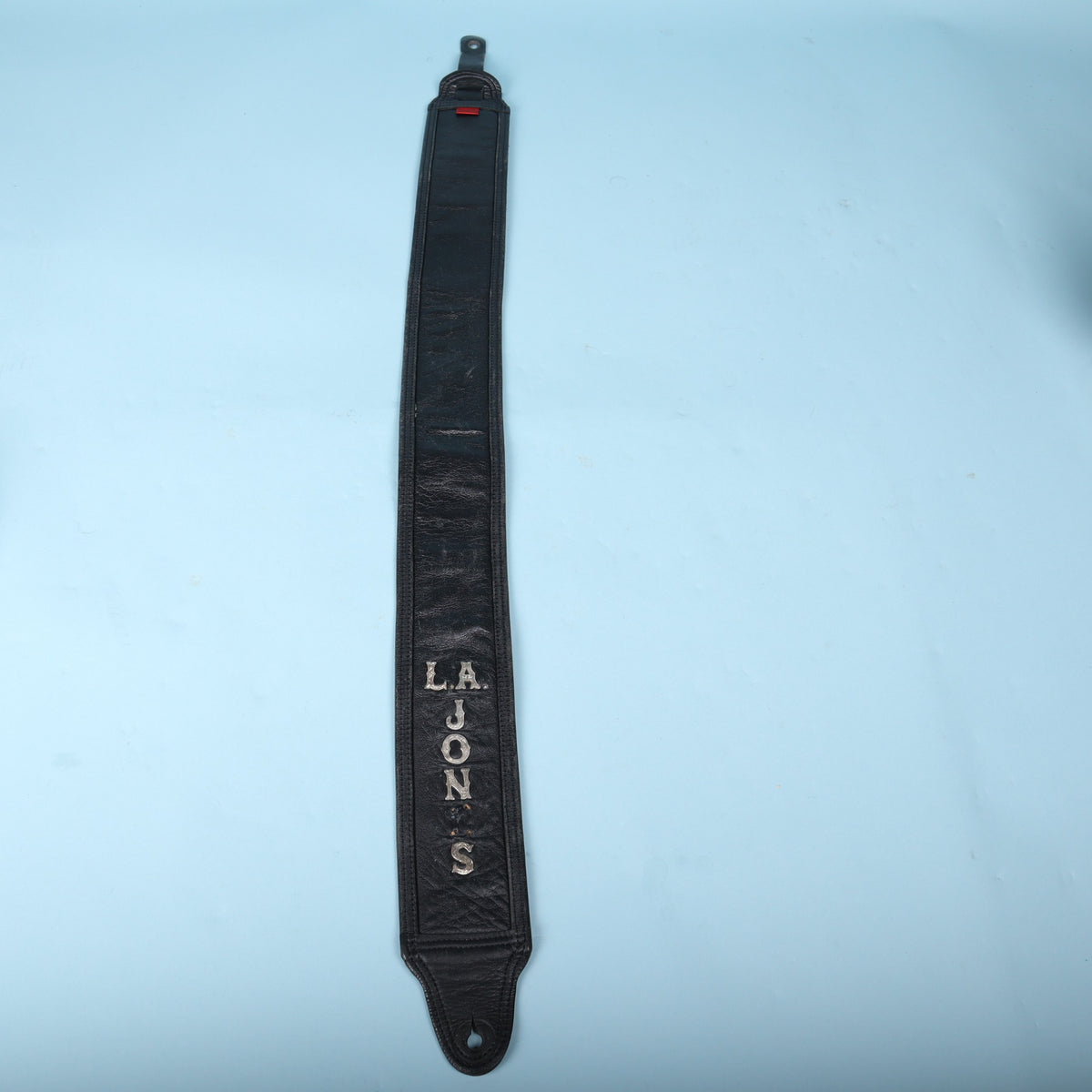 Full-length front view of the black leather strap featuring silver-tone letters spelling L.A. JONES.
