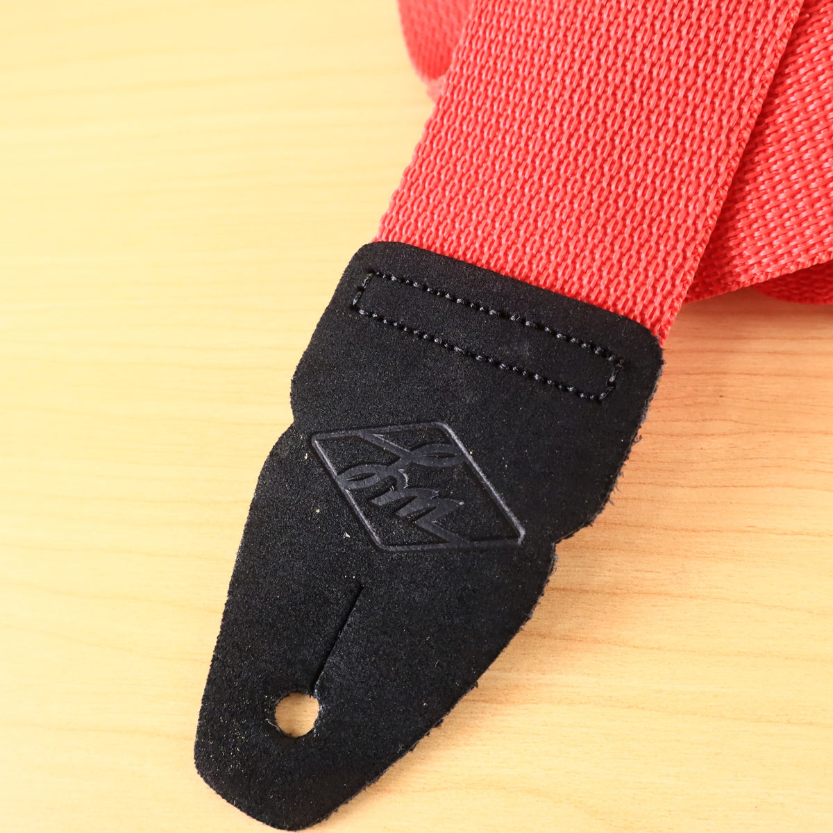 Detailed view of the embossed diamond LM logo on the black leather strap end.