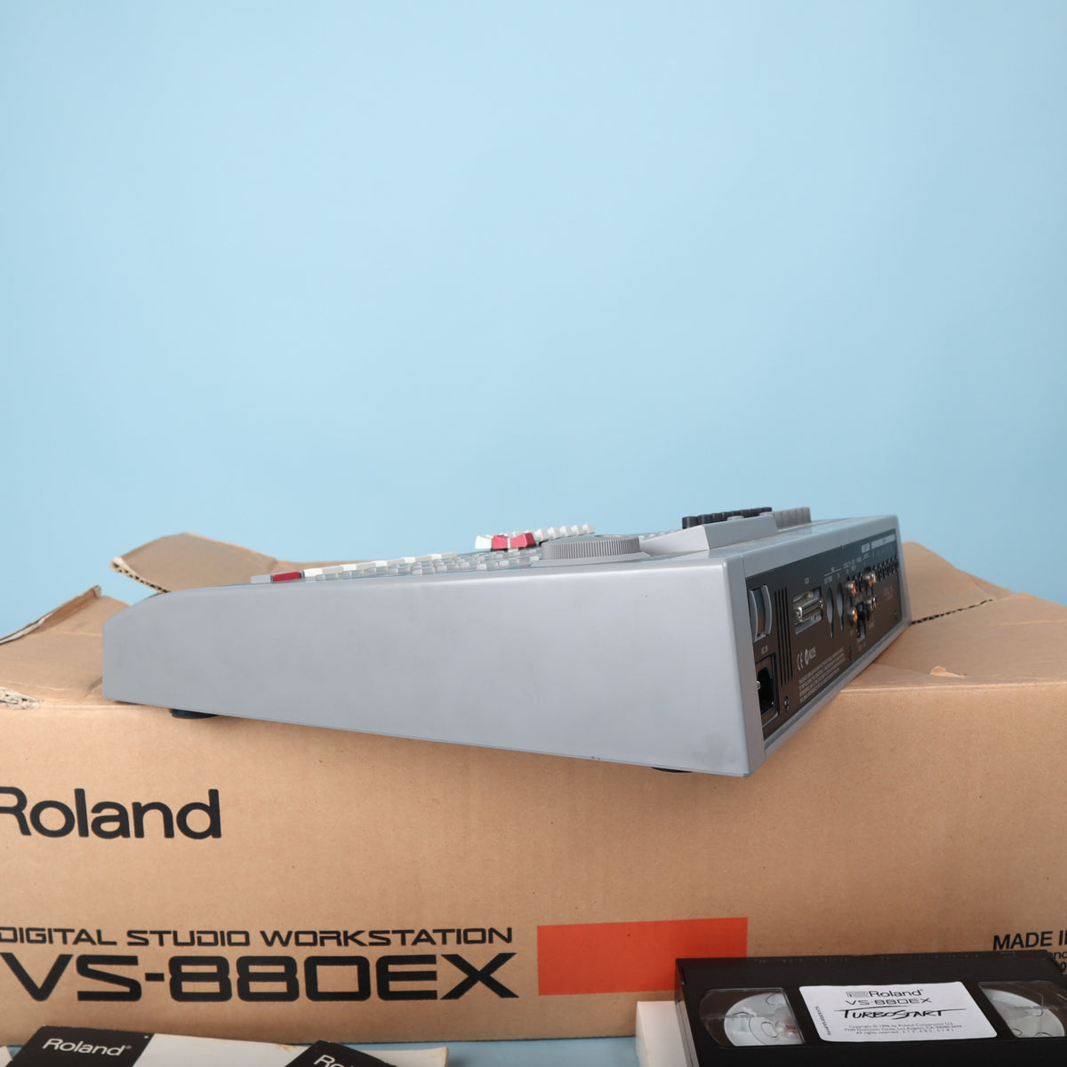 Side profile view of Roland VS-880EX gray chassis resting on its packaging box.