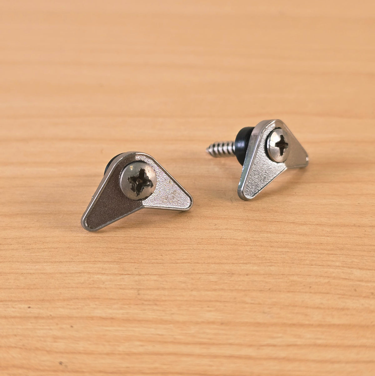 Close-up of chrome triangular guitar string retainers highlighting the finish and screws.