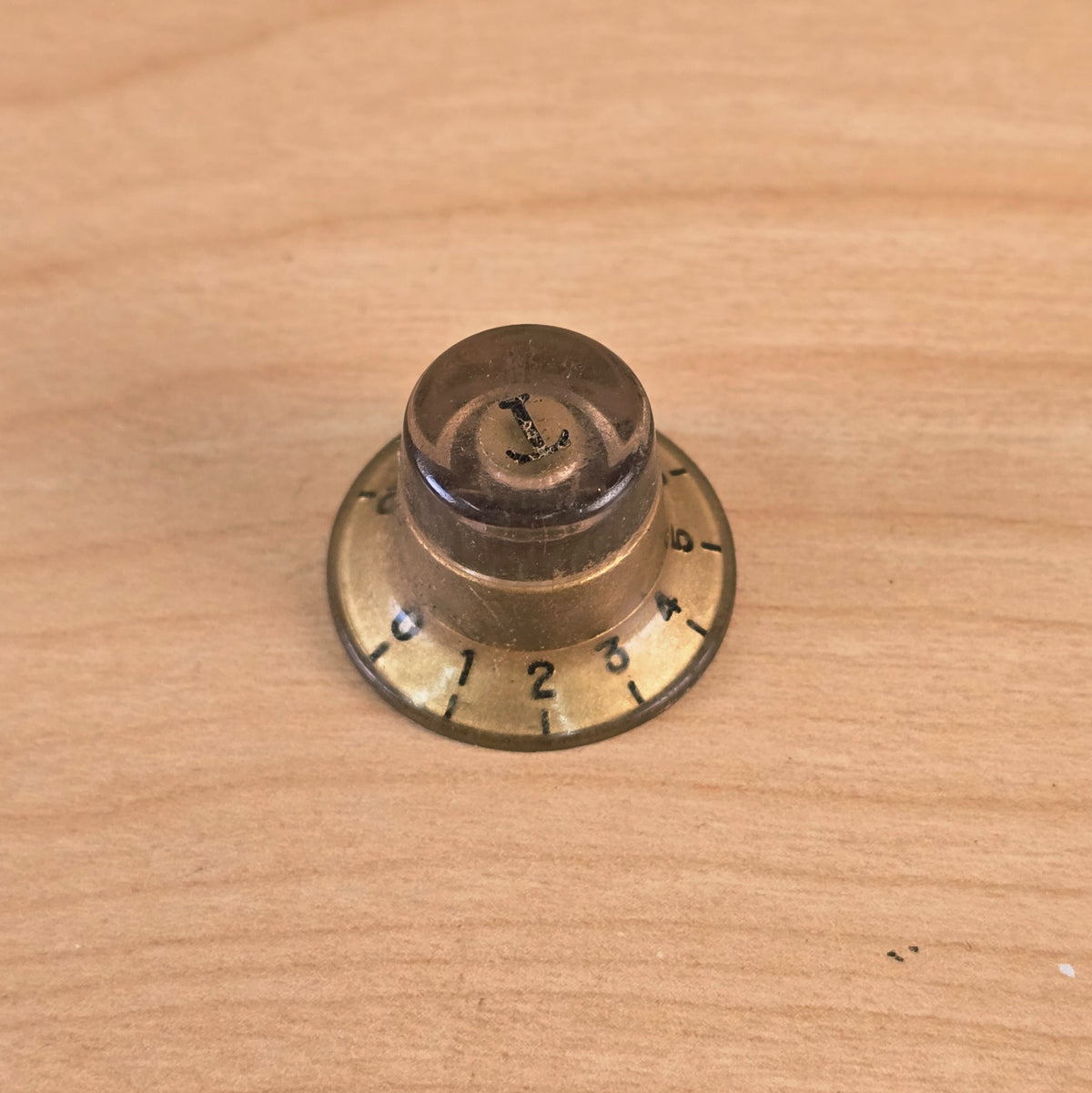 Low angle profile of gold top hat guitar control knob