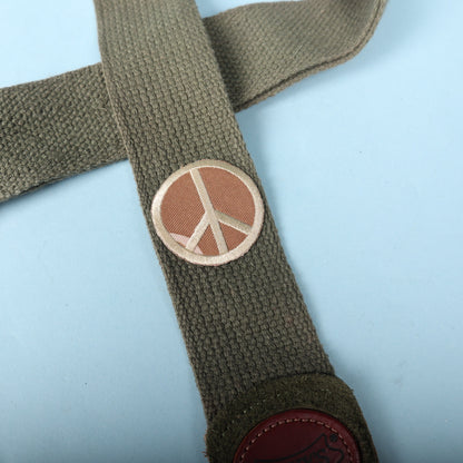 Close-up of the embroidered peace sign patch on olive green woven strap