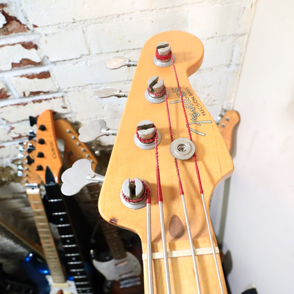 Close-up of the headstock on a workbench showing string posts and vintage tuners.