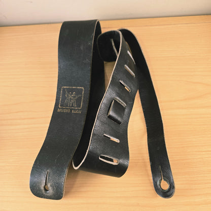Vintage Music Man black leather strap coiled showing adjustment slots and front tab