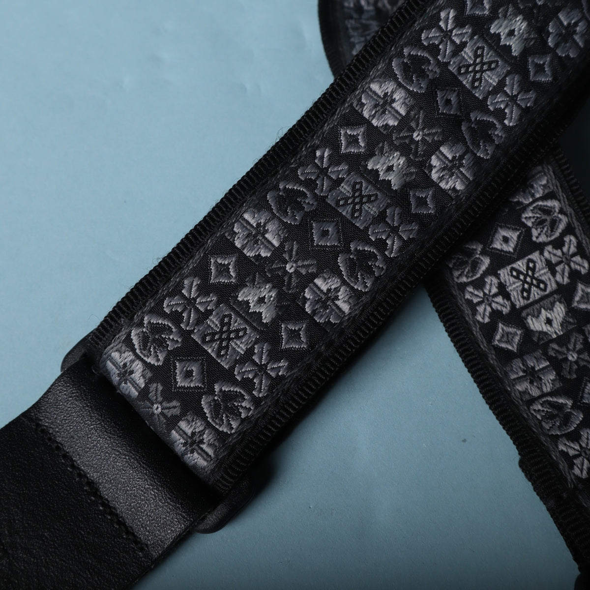 Detailed view of the grey and black geometric jacquard woven strap fabric.