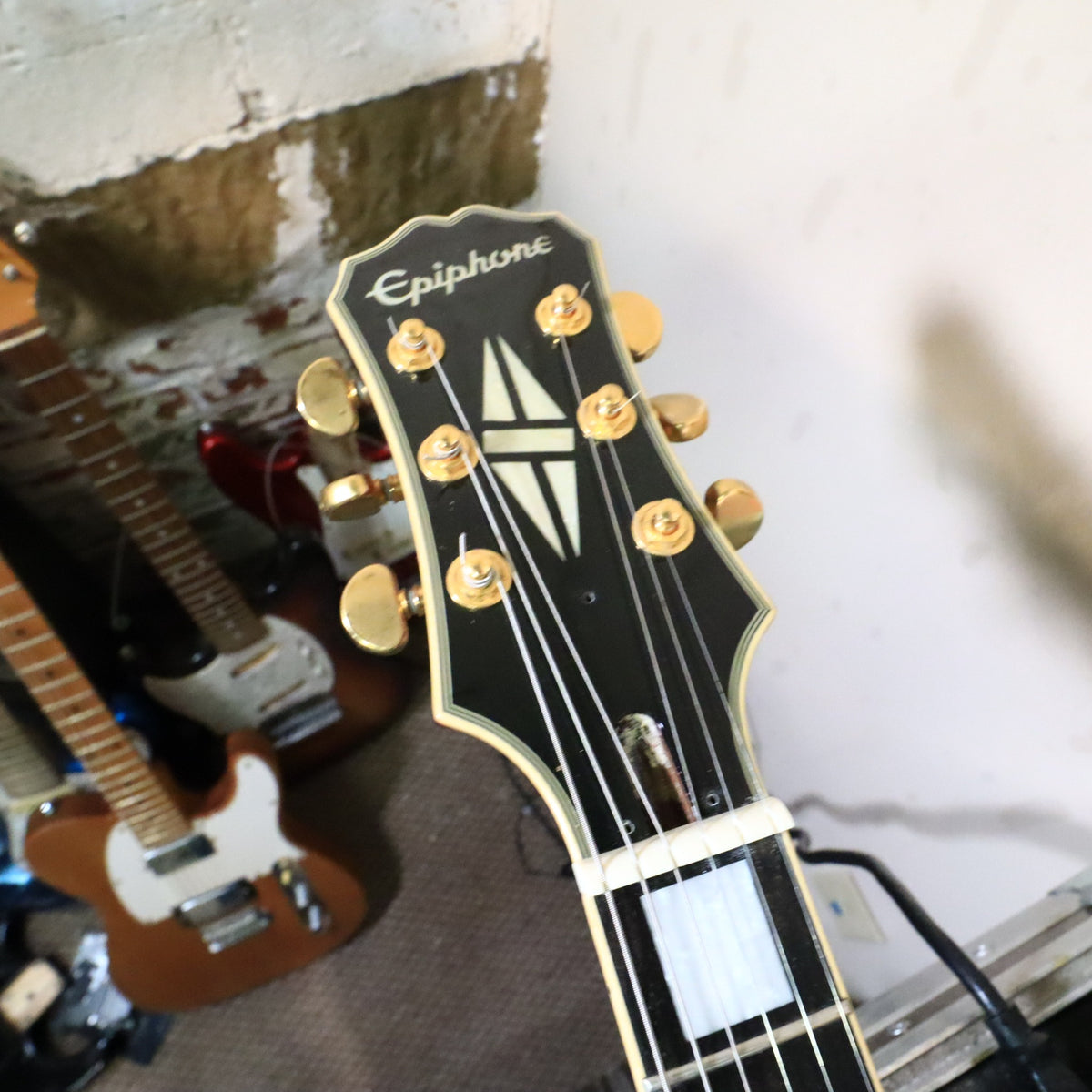 Neck and fretboard view of Epiphone Les Paul Custom on workbench