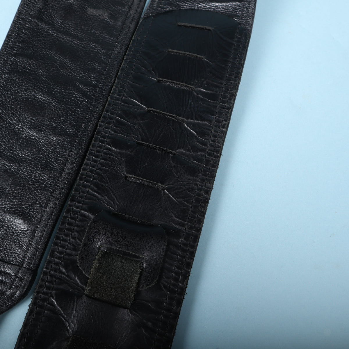 Close-up of the adjustment slots and textured black leather backing on the strap.