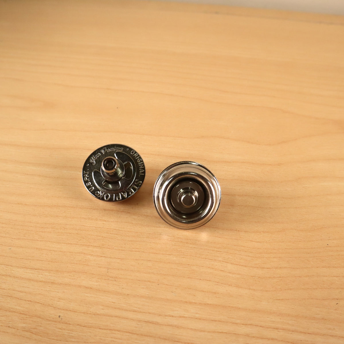 Jim Dunlop Original Straplok quick-release strap attachments, showing top engraved face and bottom cup sides.