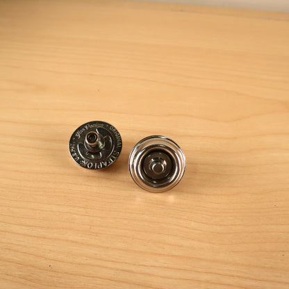 Jim Dunlop Original Straplok quick-release strap attachments, showing top engraved face and bottom cup sides.