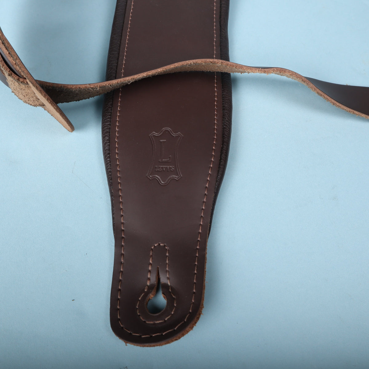 Close-up shot of the lower strap tip and reinforced stitching around the button slot