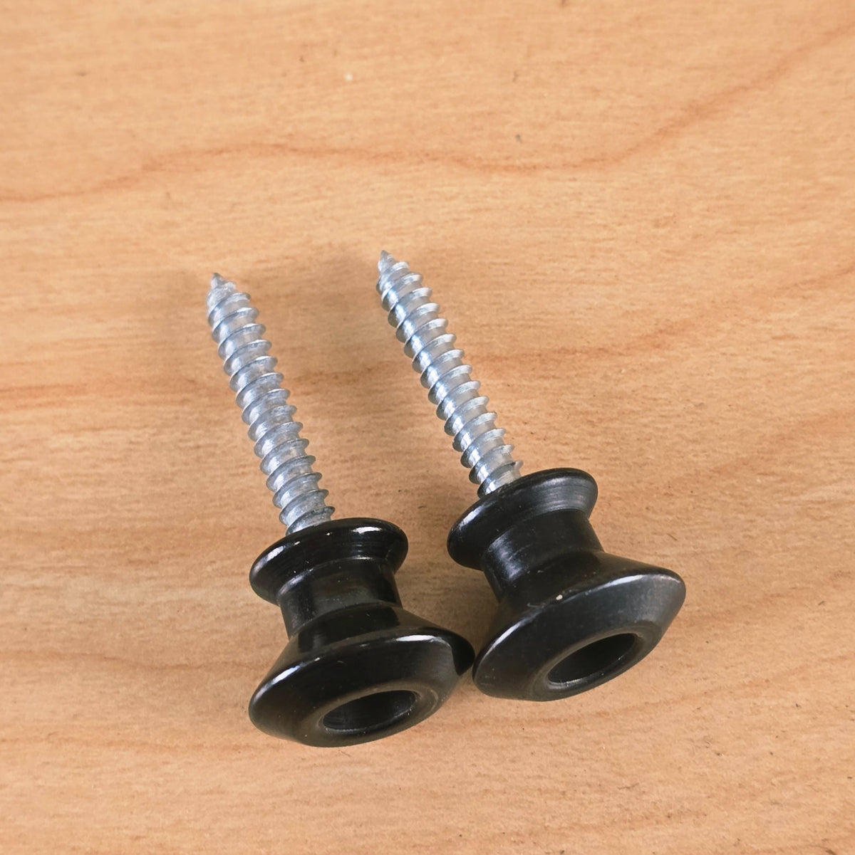 Pair of black Dunlop Straplok strap buttons viewed along the threaded mounting screws