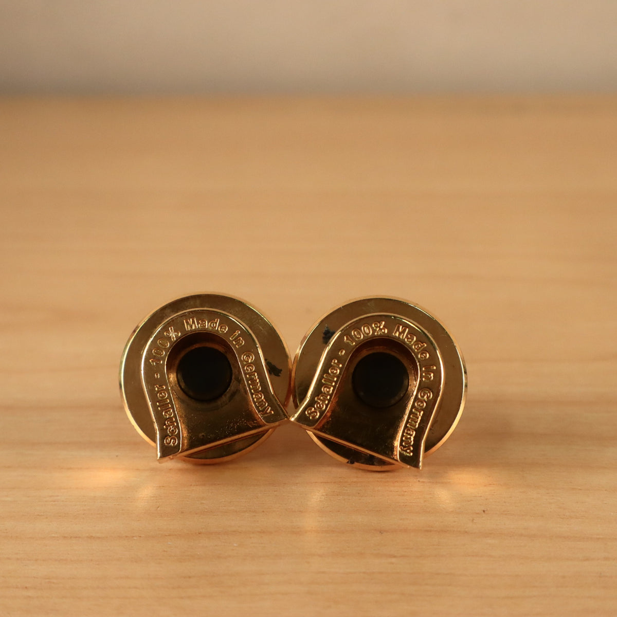 Close-up underside view of two gold Schaller strap locks highlighting the U-shaped receiver slots.