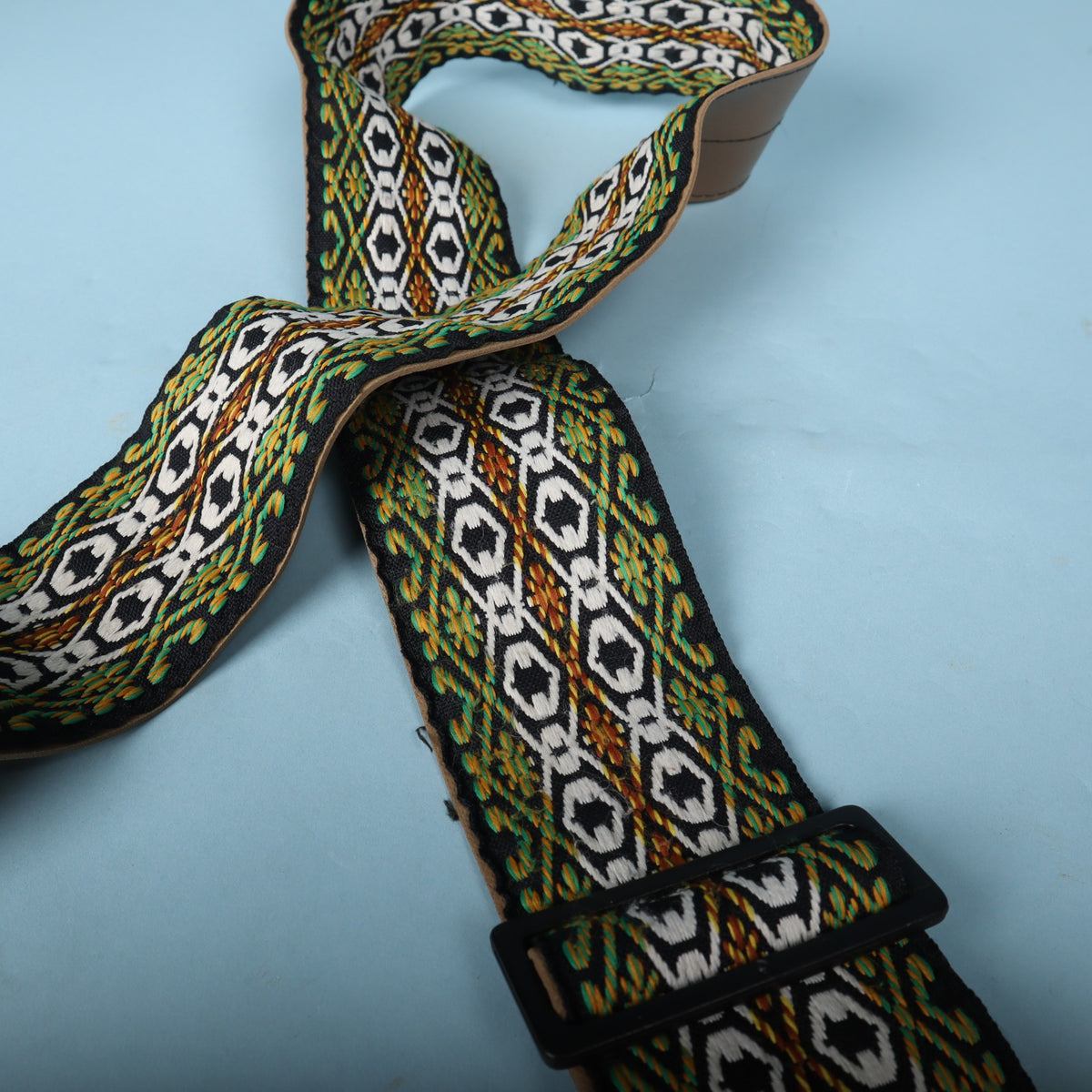 Angled view of the woven strap section and the black plastic adjustment buckle.
