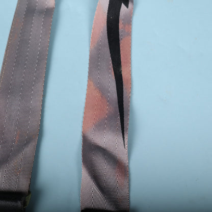 Detail of reddish discoloration and staining on the grey woven webbing alongside the black lightning bolt.
