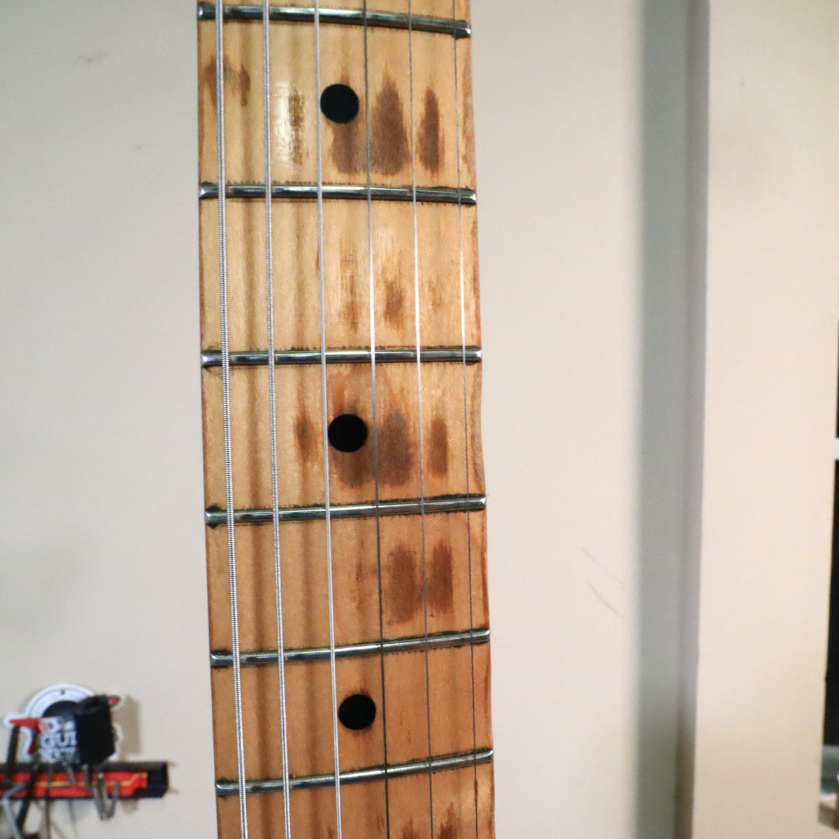 Close-up of maple fretboard showing authentic playing wear between frets