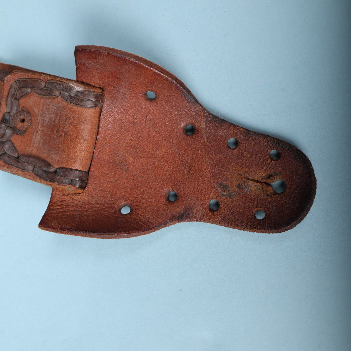 Vintage laced leather guitar strap end tab showing button slit and decorative holes