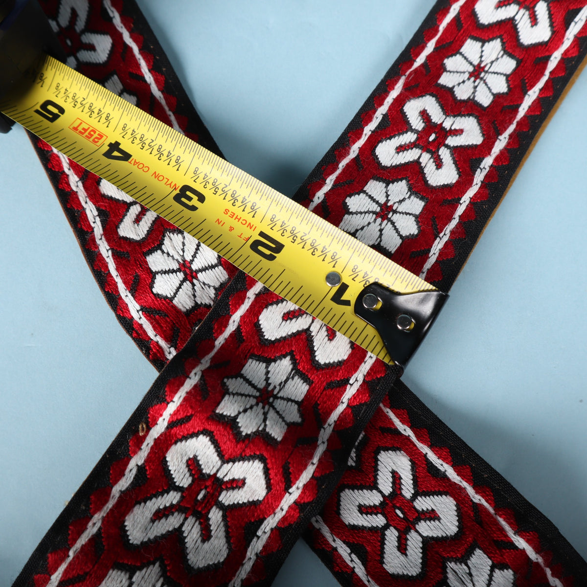 Close-up of the vintage woven guitar strap with a tape measure showing a 2-inch width