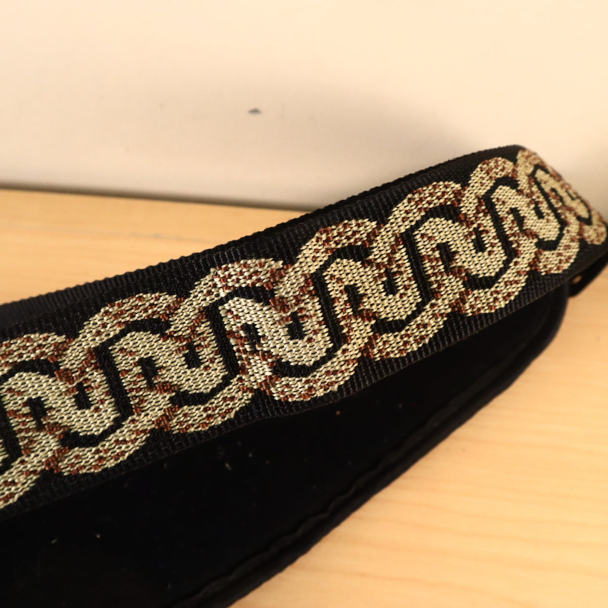 Close-up of the woven gold and brown Celtic pattern on the Planet Waves guitar strap.