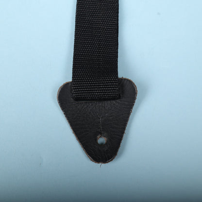 Close-up of the black leather end tab with keyhole slot attached to nylon webbing.