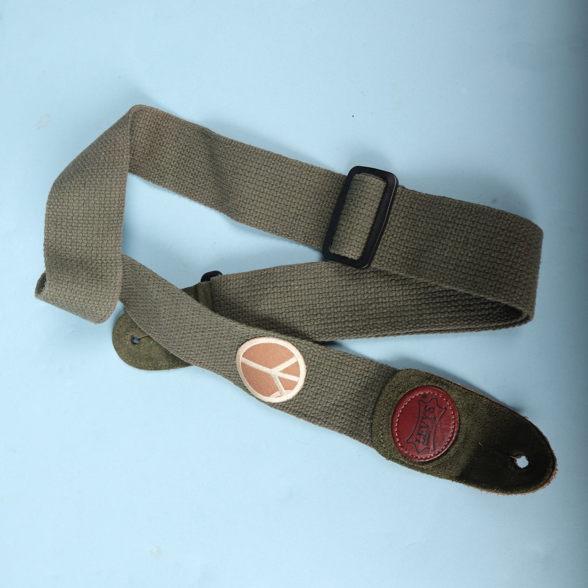 Folded Levy's cotton guitar strap showing the black adjustment slider and peace sign