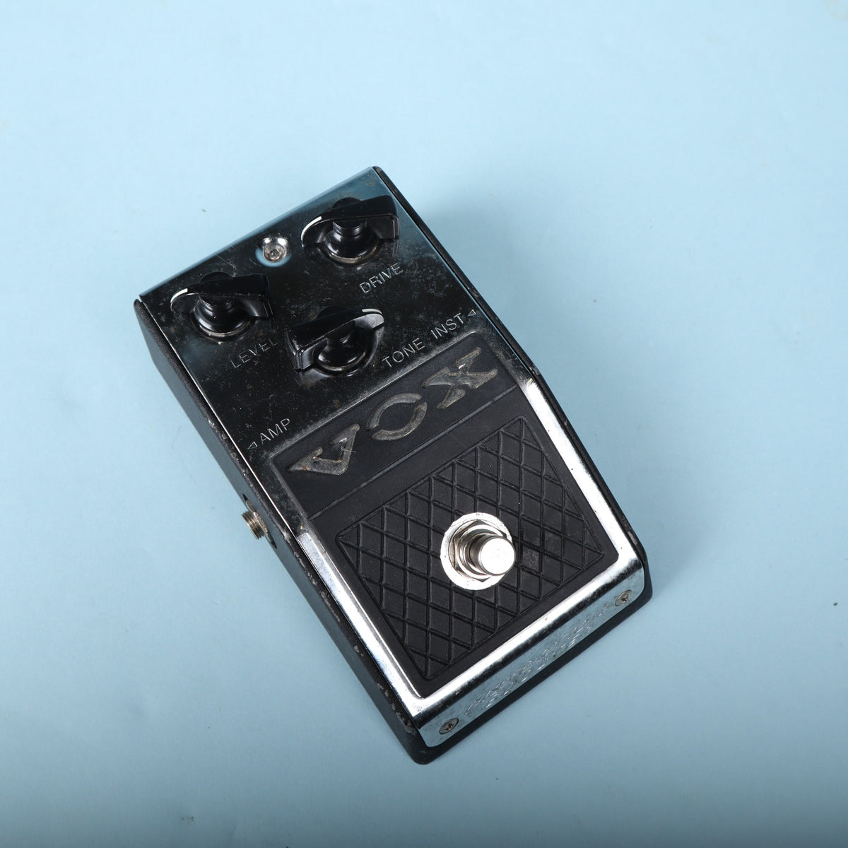 Angled top view of Vox V830 Distortion Booster against light blue background